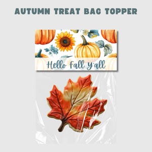 Puede incluir: Un topper para bolsa de golosinas imprimible con un tema otoñal. El topper presenta un diseño de acuarela de calabazas, girasoles y hojas. El texto en el topper dice "Hello fall y'all".