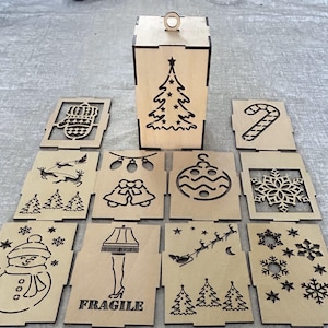 May include: A set of nine laser-cut wooden Christmas ornaments featuring various holiday themes, including a Christmas tree, a snowman, a candy cane, a snowflake, and a reindeer. The ornaments are designed to be assembled into a larger Christmas tree shape.