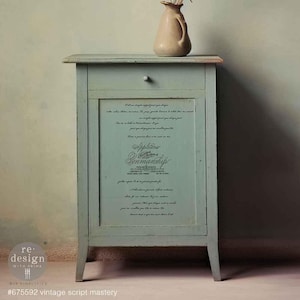 May include: A light blue cabinet with a single drawer and a decorative script panel. A beige vase sits on top. The cabinet has a distressed finish, giving it a vintage look. The text on the panel reads "Applications & Sonmanship".