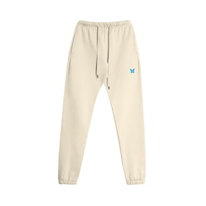 May include: Cream-colored sweatpants with a drawstring waist and elastic cuffs. A small, light blue butterfly emblem is embroidered on the left leg. The pants have two side pockets.