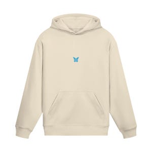 May include: Cream-colored hoodie with a front pocket and a hood. A small, light blue butterfly is embroidered on the chest. The hoodie is made of a soft material.