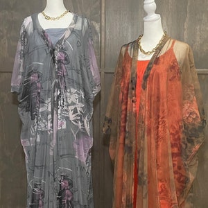 May include: Two floor-length sheer kaftans displayed on mannequins. The left kaftan is grey with a dark graphic print and a grey under-layer. The right kaftan is a burnt orange and brown floral print worn over a solid orange sleeveless dress.