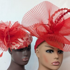 May include: Two red hats with large, ruffled, and layered netting. The hats are on mannequins' heads.