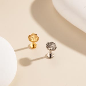 Mini piercing de concha delicado, com rosca interna em titânio, nas cores ouro e prata, estilo minimalista com inspiração oceânica.