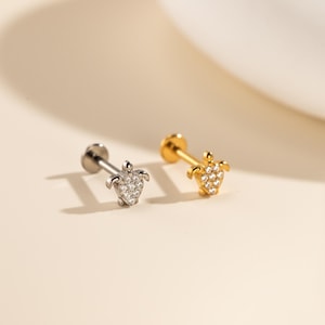 May include: Two flat-back stud earrings featuring a sea turtle design. One earring is silver-toned and the other is gold-toned. Each turtle shell is encrusted with small, clear, sparkling stones, and the studs have a straight post and flat base.