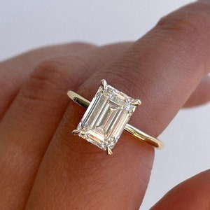 May include: A gold ring with a large, clear emerald-cut diamond.
