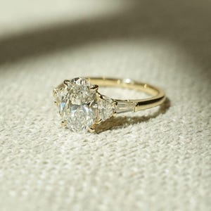Sophisticated three stone engagement ring featuring 2.05 total carat weight of oval lab created diamonds on a cathedral shank band. This stunning ring is ideal for weddings, proposals, or anniversaries—crafted for the modern bride with timeless taste.