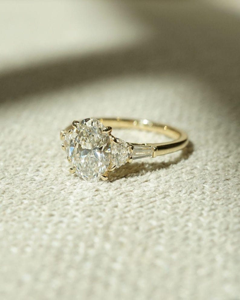 Sophisticated three stone engagement ring featuring 2.05 total carat weight of oval lab created diamonds on a cathedral shank band. This stunning ring is ideal for weddings, proposals, or anniversaries—crafted for the modern bride with timeless taste.