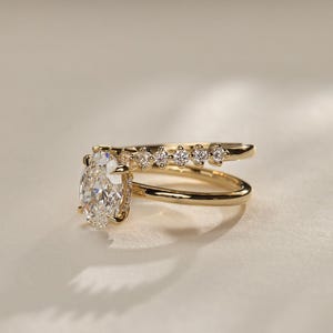 Modern 2.20 total carat weight lab grown diamond ring with an oval solitaire, hidden halo, and pave-set double dome band. This eye-catching engagement ring is perfect as an anniversary gift or a luxury promise ring for her.