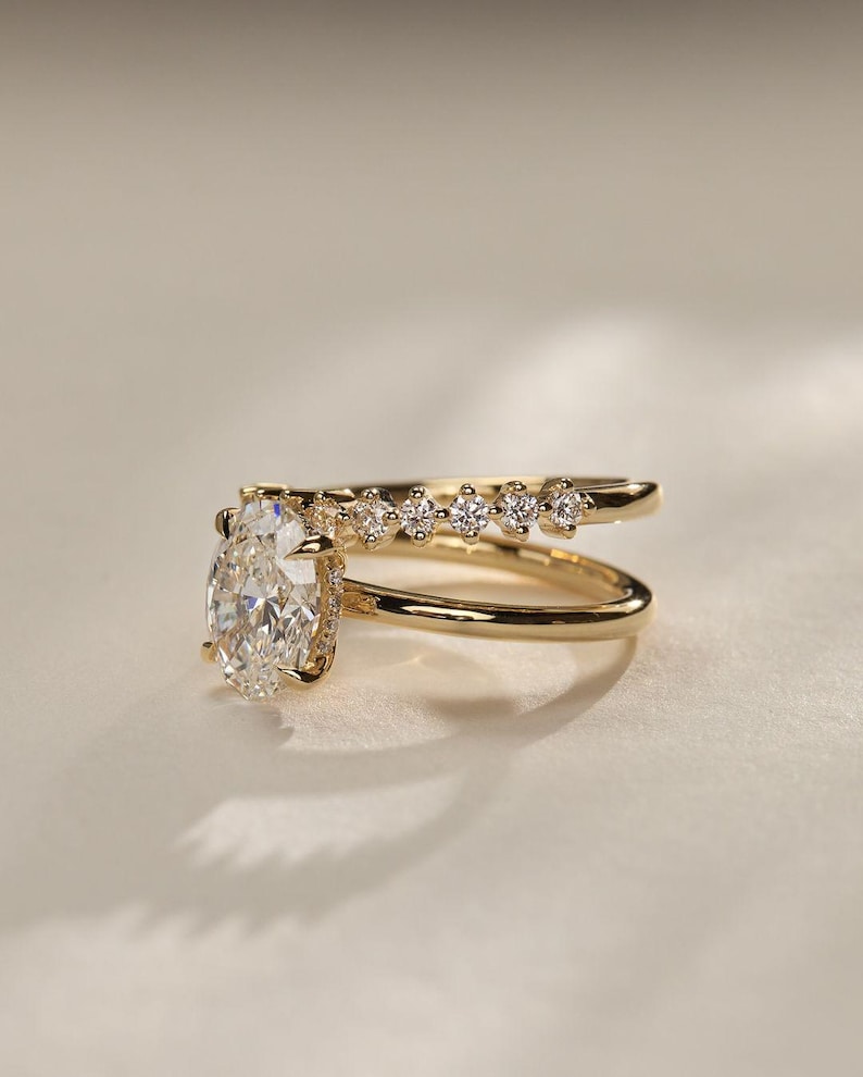 Modern 2.20 total carat weight lab grown diamond ring with an oval solitaire, hidden halo, and pave-set double dome band. This eye-catching engagement ring is perfect as an anniversary gift or a luxury promise ring for her.