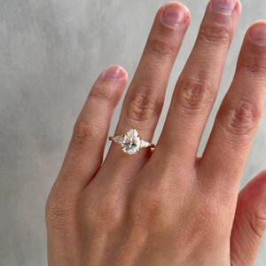 2ct pear-shaped lab grown diamond ring designed with a graceful cathedral setting and accented by two side stones. This three-stone engagement ring symbolizes lasting love and commitment, ideal for anniversaries, proposals, or weddings. Trending among Etsy’s fine lab diamond ring collections.