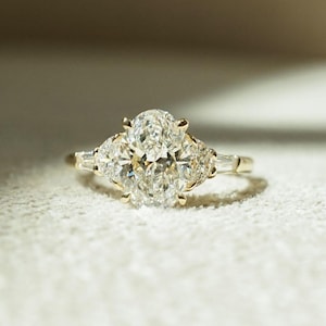 Elegant 2.05tcw oval lab grown diamond three stone engagement ring with a cathedral shank design. A forever classic ring symbolizing past, present, and future—perfect as an anniversary gift, wedding ring, or timeless keepsake for her.