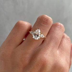 Elegant 2ct pear lab grown diamond cathedral engagement ring featuring a classic three-stone design symbolizing past, present, and future. This handcrafted wedding ring is made with eco-friendly diamonds and perfect for anniversaries or proposals. Popular on Etsy for modern yet timeless bridal styles.