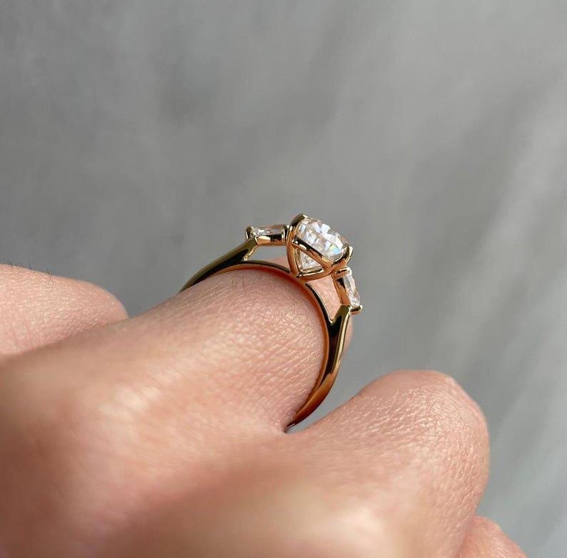 A dazzling 2 carat pear cut lab diamond engagement ring in cathedral style with a three-stone layout, perfect as a promise or wedding ring. This piece is custom-made with sustainable lab created diamonds and loved on Etsy for its emotional symbolism and modern elegance.