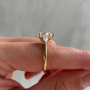 Three-stone cathedral engagement ring featuring a 2 carat pear-shaped lab grown diamond as the centerpiece. Crafted with ethical brilliance and modern elegance, this ring makes a thoughtful anniversary gift or bridal keepsake. A frequently favorited ring in Etsy’s custom fine jewelry category.