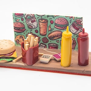 May include: A miniature food set with a cheeseburger, french fries, ketchup, mustard, and a sign with a cartoon burger and fries pattern. The set is made of polymer clay and is a great addition to any miniature food collection.