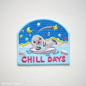 Puede incluir: Parche bordado termoadhesivo con una foca de dibujos animados en un témpano de hielo con una estrella fugaz y el texto "Chill Days" en rosa.