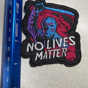 May include: Black embroidered patch with a white background. The patch features a masked figure holding a bloody knife and the text "NO LIVES MATTER".