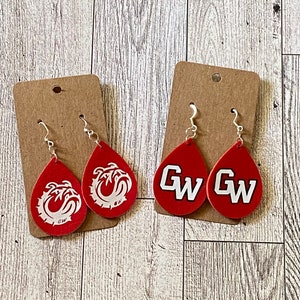 May include: A pair of red teardrop-shaped earrings with white bulldog logos. The earrings are on a brown card with silver hooks.