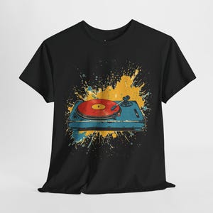 May include: Black t-shirt featuring a graphic of a vintage record player with a red vinyl record. The record player is blue with yellow and blue paint splatter in the background. A classic design for music lovers.