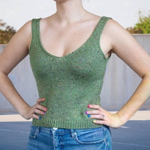 Puede incluir: Un top de tanque de punto verde con un patrón moteado. El top tiene un cuello en V y es corto.