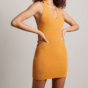 May include: A mustard yellow halter neck mini dress made of a ribbed knit fabric.