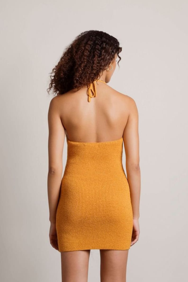 May include: A mustard yellow halter dress with a ribbed knit texture. The dress is sleeveless and has a fitted silhouette.