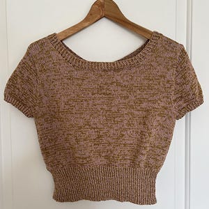 May include: A brown and pink short-sleeved knitted sweater with a round neckline. The sweater has a ribbed hem.