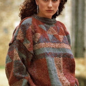 May include: A colourful, geometric patterned jumper with a crew neck. The jumper is made of a soft, textured yarn and has a relaxed fit.