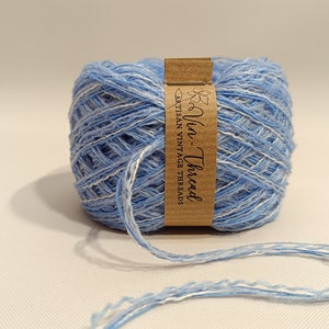K&ouml;nnte beinhalten: Eine Spule blaues und wei&szlig;es Garn mit einem braunen Etikett, auf dem "Vin-Thread Artisan Vintage Threads" steht.