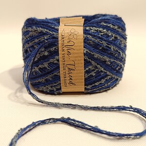 K&ouml;nnte beinhalten: Eine blaue und graue Garnrolle mit einem braunen Etikett, auf dem "Vin-Thread Artisan Vintage Threads" steht.