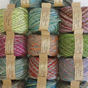 May include: A selection of yarn skeins in various colours, each with a paper label reading "Via Thread AND MORE ARTISAN VINTAGE THREADS." The yarn displays shades of blue, green, pink, orange, and grey, suitable for knitting or crochet projects.