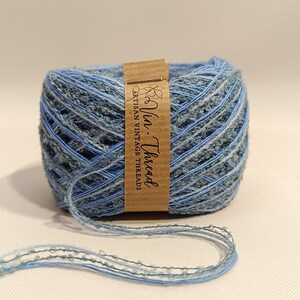 K&ouml;nnte beinhalten: Eine Spule blauen und gr&uuml;nen Garns mit einem braunen Etikett, auf dem "Via Thread Artisan Vintage Threads" steht.