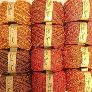 May include: Twelve spools of colorful yarn in shades of red, orange, brown, and pink. Each spool is labeled "Vin-Thread Artisan Vintage Threads".
