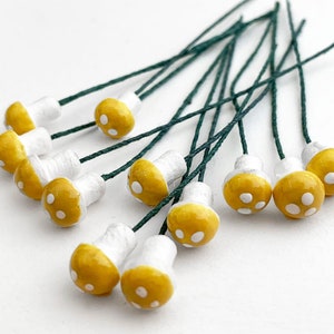 May include: A bunch of yellow and white mushroom-shaped embellishments with green wire stems. The mushrooms have white dots on the yellow tops.