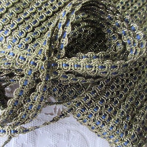 May include: Gold and blue trim with a woven pattern. The trim is made of a shiny gold thread and a dark blue thread.