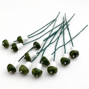 May include: A bunch of green and white mushroom-shaped embellishments with wire stems. The mushrooms have white dots on the top.