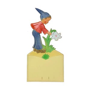 May include: A vintage paper notepad with a whimsical illustration of a boy in a blue hat and red shirt picking a white flower. The notepad is yellow with a white border and has two holes for binding.