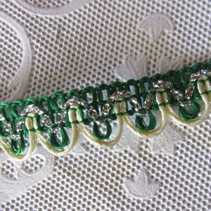 May include: Green and cream trim with silver glitter accents. The trim has a scalloped edge.