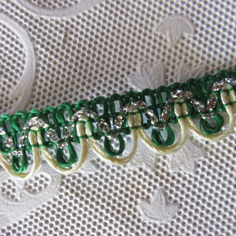 May include: Green and cream trim with silver glitter accents. The trim has a scalloped edge.