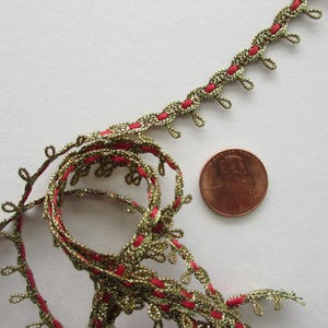May include: Close-up of decorative trim with gold and red accents. The trim has a looped edge and a red center. A penny is next to the trim for size reference.