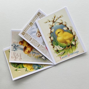 May include: A collection of vintage Easter greeting cards. The cards feature illustrations of chicks, bunnies, and floral elements. One card reads "Easter Greetings" in red script. The cards have a cream-colored background.