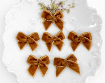 May include: Six small brown velvet bows on a white plate with a floral design.