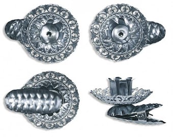 May include: Four silver metal candle holders with a decorative design. Each holder has a clip on the side to attach to a surface.