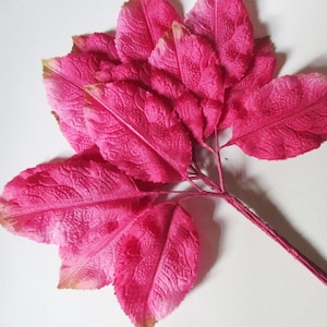 May include: A bunch of bright pink artificial leaves with a wire stem. The leaves have a textured surface and are arranged in a cluster.