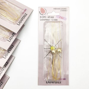 May include: A package of 2 packs of gold-colored metal wire centerpieces for making Christmas ornaments. The package says "8 CÍPŰ - 60 MM LATAPERLE - 12 MM 2 KS".