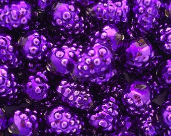 May include: A close-up of a collection of shiny, purple, glass beads. The beads are shaped like small berries and have a smooth, glossy finish.