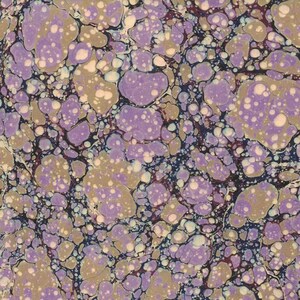 May include: A marbled paper design featuring a pattern of organic shapes in shades of lavender, olive green, and cream, set against a dark blue background. The design has a speckled appearance, with small white dots scattered throughout the colored areas.