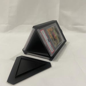 Op de afbeelding: Een zwarte driehoekige display-doos voor trading cards. De doos is open en laat drie vakken voor kaarten zien. De doos heeft een verwijderbare basis.