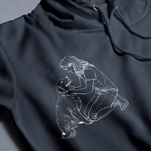 May include: A white line drawing of a person kneeling and petting a dog. The image is printed on a dark blue hoodie.